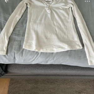Vit ribbad långärmad topp med snörning - Säljer en vit tröja i ett mycket bra skick 