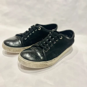 Svarta fetta sneakers från Lanvin Storlek 40-41 - Snygga svarta sneakers från Lanvin med vit sula och snörning. Skorna har en stilren design med en rund tå och är perfekta för en avslappnad look. 