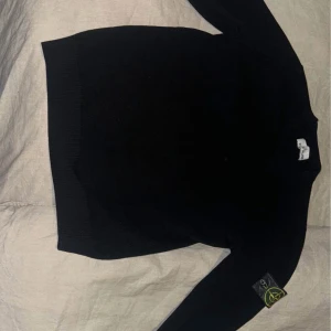 Svart tröja från Stone Island - Säljer en stilren svart tröja från Stone Island. Tröjan har långa ärmar och en klassisk design med ribbade muddar vid ärmslut och nederkant. Perfekt för en minimalistisk look.