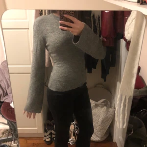 Grå stickad tröja - Säljer en stilren grå stickad tröja med långa ärmar. Perfekt för kyligare dagar och enkel att matcha med olika outfits. Tröjan har en klassisk passform och ribbade muddar vid ärmslut och nederkant. Ärmarna går snyggt ner över händerna och ger en fin form i midjan💗💗