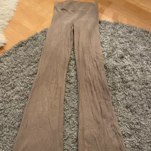 Beige ribbade byxor från H&M - Snygga beige ribbade byxor från H&M med hög midja och bootcut-stil. Perfekta för en avslappnad look med en skön passform. Tillverkade i ett mjukt och stretchigt material för extra komfort.