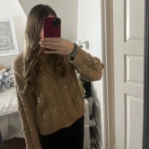 Beige stickad tröja från Zara - Säljer en snygg beige stickad tröja från Zara med flätmönster och pärldetaljer. Tröjan är i mycket bra skick