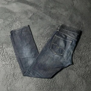 Mörkblå jeans från Replay - Snygga mörkblå jeans från Replay med en klassisk femficksdesign. De har en straight passform och är tillverkade i slitstarkt denim. Perfekta för en avslappnad stil.Storlek 34/34