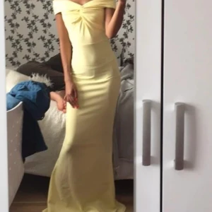 Gul balklänning - Elegant gul långklänning med en stilren offshoulder-design. Perfekt för sommarens festligheter. Klänningen har en smickrande passform och är tillverkad i ett mjukt material som ger en bekväm känsla.