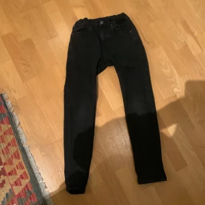 Svarta jeansbyxor - Snygga svarta jeansbyxor med en tight passform. De har en klassisk design med fem fickor och knappgylf. Perfekta för en stilren look.