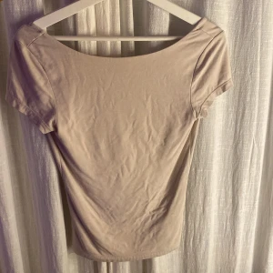 Beige topp från Gina Tricot - Säljer en stilren beige topp från Gina Tricot i storlek S. Toppen har korta ärmar och en djup öppen rygg som ger en elegant touch. Inga defekter! Och knappt använd