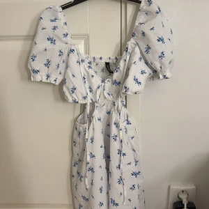 Vit blommig klänning från H&M Divided - Jätte fin klänning ifrån hm säljer den för att den är påväg att bli förliten. Den har inga tecken på användning❤️