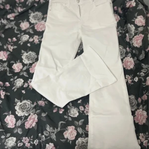 Vita bootcut jeans - Snygga vita bootcut jeans med hög midja. Perfekta för en stilren look. De har klassiska fem fickor och knappar framtill.
