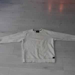 Vit tröja från Brave Soul - Säljer en stilren vit tröja från Brave Soul med ett diskret mönster. Tröjan har långa ärmar och rund halsringning. Perfekt för en avslappnad look.