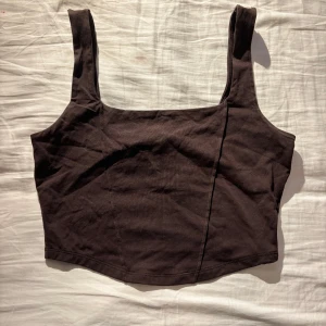 Brun topp från Gina Tricot - Snygg brun korsett-topp från Gina Tricot i bomull och elastan. Toppen har breda axelband och en enkel design som passar perfekt till allt möjligt