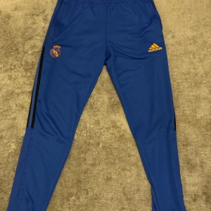 Blå träningsbyxor med Real Madrid logga  - Snygga blå träningsbyxor med ett  Real Madrid logga och Perfekta för fotbollsträning eller annan sportaktivitet. Bra kvalité och bra pris bara 120 spänn kostar original 700 