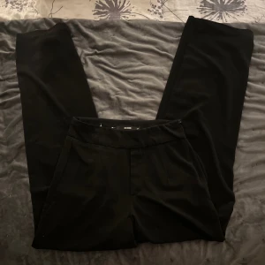 Svarta byxor från BikBok - Snygga svarta byxor från BikBok i storlek XS. De har en klassisk design med rak passform och är perfekta för en stilren look. Byxorna har en diskret dragkedja och knapp framtill.