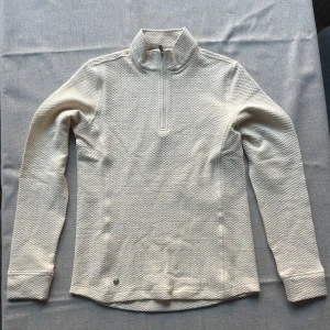 Vit långärmad tröja med dragkedja - Säljer en stilren vit långärmad tröja med dragkedja i kragen. Tröjan har en diskret textur och är perfekt för kyligare dagar. Passar bra till både jeans och kjol. Perfekt för en avslappnad men ändå snygg look.