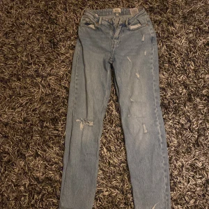 Blå jeans med slitningar - Snygga blå jeans med slitningar för en trendig look. De har en klassisk femficksdesign och en bekväm passform. Perfekta för en avslappnad stil.