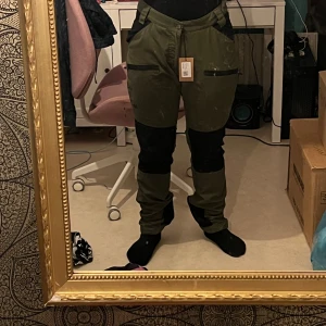 Gröna cargopants med svarta detaljer - Snygga gröna cargopants med svarta förstärkningar på knän och bak. Byxorna har flera praktiska fickor och en bekväm passform. Perfekta för en avslappnad och cool stil. #outdor 