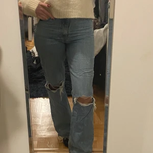 Blå jeans med slitningar - Säljer ett par blå jeans med slitningar på knäna. De har en lite utsvängd passform längst ner med en mellanhög midja. Använda några fåtal gånger men annars i bra skick, långa på mig som är 167💕💕