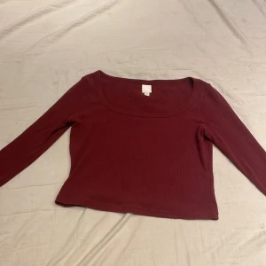 Vinröd ribbad topp från H&M - Säljer en vinröd ribbad topp från H&M med långa ärmar och rund halsringning. Perfekt för en stilren look. Passar bra till både jeans och kjol. 🌟