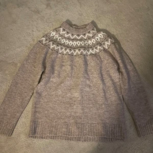 Beige stickad tröja med mönster - Säljer en mysig beige stickad tröja med ett fint vitt mönster runt halsen. Tröjan har långa ärmar och ribbstickade muddar vid ärmslut och nederkant. Perfekt för kyliga dagar! Pris kan diskuteras vid snabb affär 💝 aldrig använd! 