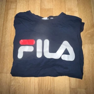Mörkblå t-shirt från Fila - Snygg mörkblå t-shirt från Fila med stort logotryck i vitt och rött på framsidan. 