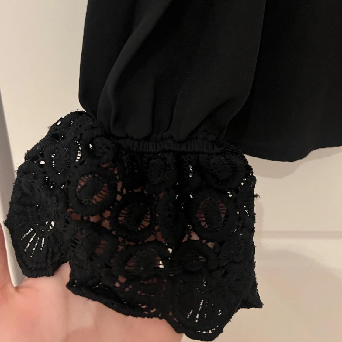 Svart blus med blommig design på armen - 1