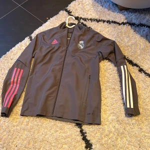 Grå träningsjacka från Adidas - Säljer en grå tränings tröja men real Madrid logga. Mycket bra skick. Säljer för att den är för liten 