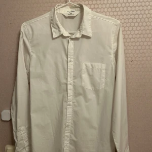 Vit skjorta från H&M - Säljer en junior vit skjorta från H&M, passar ålder 13-14 år.  Skjortan är i ett lättstruket material, perfekt för en stilren look. Den har knappar framtill och en traditionell krage.