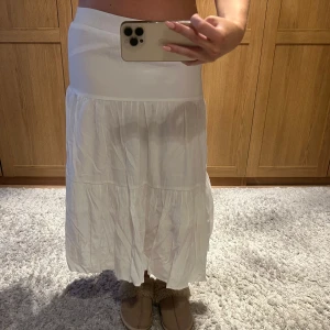 Vit långkjol - Säljer en stilren vit långkjol med en luftig och bekväm passform. Jag är 160 och kjolen är lite kortare än ankel.