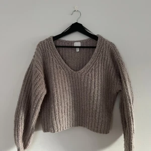 Grå stickad tröja från H&M - Säljer en mysig grå stickad tröja från H&M. Tröjan har en v-ringad design med långa ärmar. Perfekt för kyliga dagar! Se bilder för skick, någon noppra