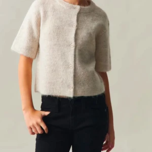 Beige stickad kofta - Säljer en mysig beige stickad kofta med kortärmade ärmar och knappar framtill. Perfekt för en avslappnad stil och passar bra till jeans eller kjol.