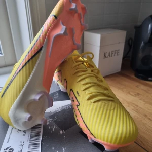 Nike airzoom fotbollskor - Snygga gula fotbollsskor aldrig använda från Nike med orange och svart detaljer. Säljer för dem inte passar. Skorna har en modern design med snörning och en slitstark sula med dobbar för bra grepp på planen. Perfekta för fotbollsspelare som vill sticka ut på planen.