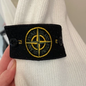 Vit ribbad tröja från Stone Island  - Säljer en stilren vit ribbad tröja från Stone Island med v-ringning. Tröjan har långa ärmar och en logga på ärmen. Perfekt för en avslappnad men ändå snygg look. Jag vet inte om den är äkta därav priset men det är en superfin tröja💕 lappen är avklippt