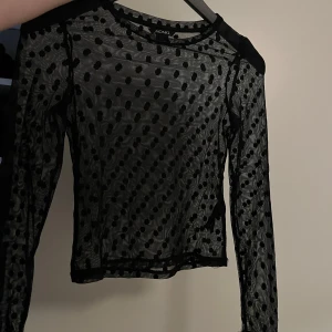 Svart prickig mesh-topp från Monki - Säljer en superfin svart mesh-topp från Monki i storlek XS. Toppen är genomskinlig med ett prickigt mönster och har långa ärmar. Perfekt för lager-på-lager eller en utekväll! 🖤