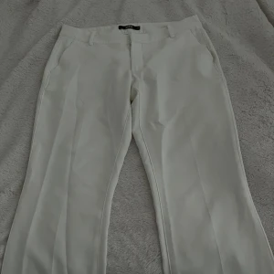 Vita kostymbyxor från BikBok - Säljer ett par omtyckta lågmidjade vita kostymbyxor från BikBok i storlek 40. Byxorna har en klassisk design med raka ben och diskreta fickor. Perfekta för vardag och fest. Sitter lågmidjade på mig som vanligt vis har 38!! Använda 1 gång. Som nya!!