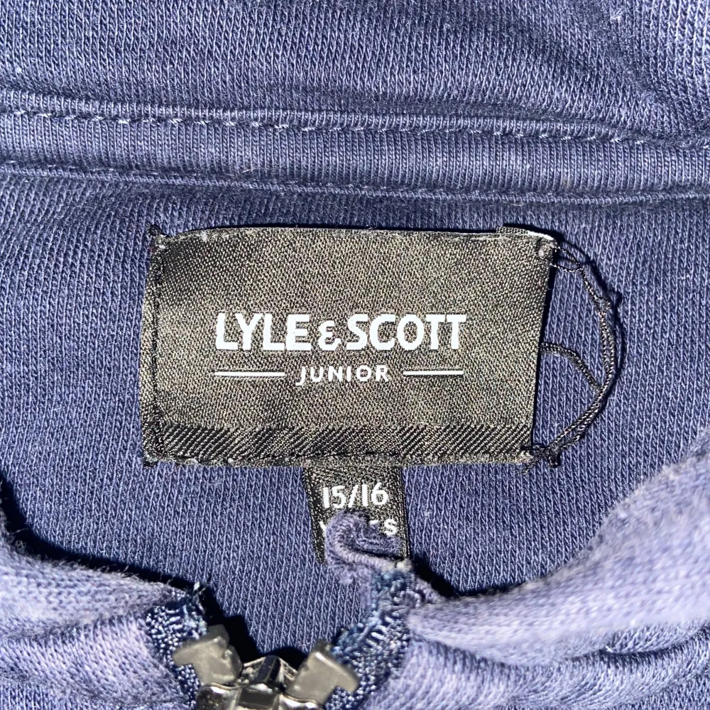 Säljer en snygg mörkblå hoodie från Lyle & Scott i storlek 15/16. Den har en dragkedja framtill och en gul broderad logga på bröstet. Perfekt för både vardag och chill. Huvan gör den extra mysig! (Accepterar endast Swish pga lurendrejerier) (Check gärna in kläder från min profil och köp tillsammans för ett rabatterat pris). Neuletakit & Villapaidat.