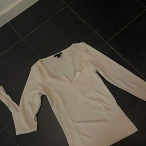 crèmevit topp  - Säljer en crèmevit långärmad topp i mycket bra skick. Den har en v-ringad design som ger en elegant touch. använd endast 2 gånger 