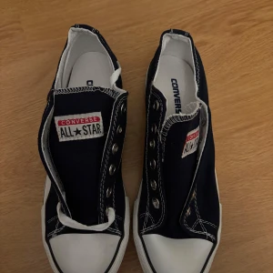 Svarta Converse All Star sneakers - Säljer ett par klassiska svarta Converse All Star sneakers med vit sula och tåhätta. Skorna har snörning och det ikoniska logotypmärket på plösen. Perfekta för en avslappnad stil. Aldrig använda. Säljer med snöret till. 