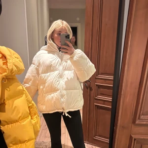 Vit pufferjacka - Säljer en snygg vit pufferjacka med dragkedja och huva. Jackan är oversized och perfekt för kalla dagar. Den har en justerbar dragsko i nederkanten för extra värme och stil. Den är i storlek L men jag är vanligen en Xs/S och tycker inte den är för stor.