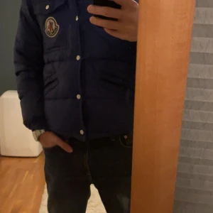 Blå k2 jacka från Moncler - Snygg blå pufferjacka från Moncler med knappar och dragkedja. Jackan har en broderad logotyp på bröstet och är tillverkad i polyamid. Perfekt för kyliga dagar. Är i perfekt skick om man inte tänker på sista bilden. Moncler k2 jacka, org pris runt 6500kr. Den är i storlek 2 vilket är runt s-m, passar för båda. Pris kan diskuteras