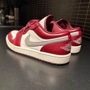 Nike Air Jordans i röd och vit - Snygga Nike Air Jordans i röd och vit med klassisk design. Skorna har en vit bas med röda detaljer och den ikoniska Nike-loggan i grått på sidan. Perfekta för en sportig look.