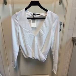 Vit och svart omlottopp från Bik Bok - Säljer två stilrena omlottoppar från Bik Bok i storlek XS. En i vit och en i svart. Båda har långa ärmar och en v-ringning. Perfekta för både vardag och fest!