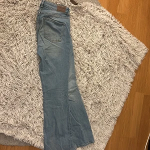 Ljusblå bootcut jeans - Snygga ljusblå bootcut jeans med klassisk femficksdesign. Perfekta för en avslappnad stil med en touch av retro. De har en bekväm passform och är tillverkade i ett mjukt denimtyg. I storlek L. Säljer dessa då dem är alldeles för stora för mig 