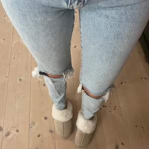 Ljusa jeans med slitningar - Säljer ett par ljusa jeans med snygga slitningar vid knäna. De är högmidjade och har en tight passform som sitter perfekt. Perfekta för en avslappnad vardagslook eller en utekväll. Passar bra till både sneakers och klackar!