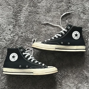 Svarta Converse  - Säljer ett par klassiska svarta Converse All Star sneakers i bra skick. De har en hög modell med vit sula och vita snören. Skorna är använda några gånger men varsamt och har inga defekter. 