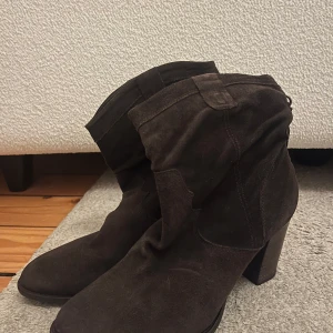 Bruna mockaboots med klack - Snygga bruna boots i mocka med klack och dekorativa detaljer. Perfekta för höst och vinter, dessa boots har en stilren design som passar till många outfits. Super snygga! 