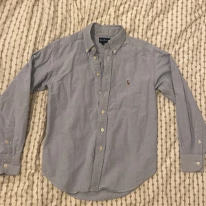 Ljusblå skjorta från Ralph Lauren - Säljer en klassisk himmelblå skjorta från Ralph Lauren i mycket bra skick. Skjortan har långa ärmar och knappar framtill samt en broderad logga på bröstet. Perfekt för både vardag och fest! 🐎