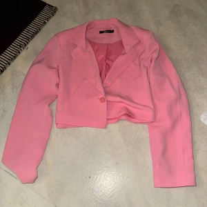 Rosa kavaj - Snygg rosa kavaj med en enkel knapp framtill. Den är croppad och har långa ärmar, perfekt för en trendig look. Passar S-l beroende på hur man vill att den ska sitta.