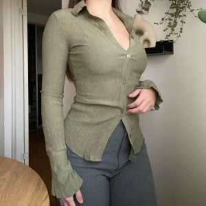 Olivgrön skjorta  - Snygg olivgrön skjorta från Bershka i ett krinklat material. Skjortan har en figurnära passform med långa ärmar och knappar framtill. Knappt använd.