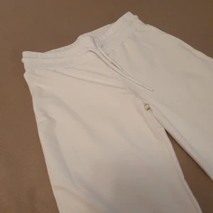 Vita mjukisbyxor från Lager 157 - Säljer ett par vita EBBA mjukisbyxor från Lager 157 i storlek S. De är superbekväma med en elastisk midja och dragsko. Lågmidjade med flare (men går att ha som normal midja också) 💛 Perfekta för en avslappnad dag hemma eller en snabb tur till affären. Byxorna är i mycket bra skick och redo för en ny ägare!  
