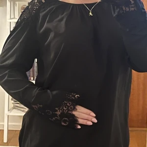 Svart blus med spetsdetaljer - Snygg svart blus med långa ärmar och spetsdetaljer. Perfekt för både vardag och festliga tillfällen. Blusen har en lös passform och är i ett mjukt och bekvämt material. Upplevd storlek: S. Hör av er vid eventuella frågor. 💞💞
