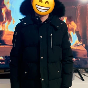 Svart dunjacka från Moose Knuckles XL barn - Säljer en svart dunjacka från Moose Knuckles i mycket bra skick. Jackan har en fluffig pälsfodrad huva och flera praktiska fickor med dragkedja. Perfekt för kalla vinterdagar! 🖤köpt på NK sparsamt använd endast en säsong. Pris kan diskuteras.
